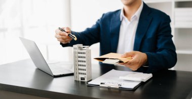 Real estate broker agent presenting and consult to customer to decision making sign insurance form agreement, home model, concerning mortgage loan offer