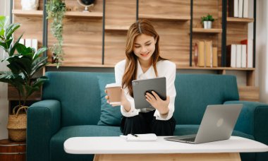 İş kadını matematik finansmanı, vergi, rapor, muhasebe, istatistik ve analitik araştırma kavramını yurt merkezindeki koltukta yapmak için tablet ve dizüstü bilgisayar kullanıyor.