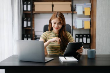 Modern ofiste otururken dijital tablet kullanan Asyalı bir iş kadını 