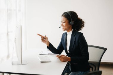 Kulaklıklı bir çağrı merkezi operatörü müşteriyle konuşuyor. Afrikalı kadın müvekkil danışmanı. Müşteri destek servisi 