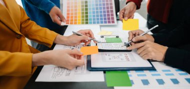  UX geliştiricisi ve ui tasarımcıları modern ofiste müşteri özeti ve renk kodu ile mobil uygulama arayüzü kablo tasarımı hakkında beyin fırtınası yapıyorlar.