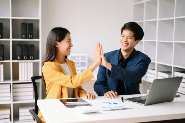 Genç Asyalı iş adamları yaratıcı iş adamları başarıyı kutluyor ve ofiste yaratıcı tasarım planlıyorlar.