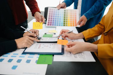  UX geliştiricisi ve ui tasarımcıları modern ofiste müşteri özeti ve renk kodu ile mobil uygulama arayüzü kablo tasarımı hakkında beyin fırtınası yapıyorlar.