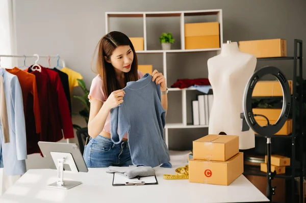 Moda blogcusu kavramı, genç Asyalı kadın video yayınında kıyafet satıyor. Akıllı telefon ya da tablet kullanarak küçük işletme KOBİ 'si kurun.