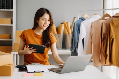 Moda blogcusu kavramı, genç Asyalı kadın video yayınında kıyafet satıyor. Tablet ve dizüstü bilgisayar kullanarak küçük işletme KOBİ 'si kurun.