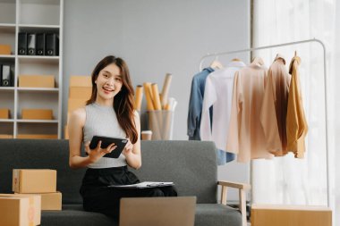 Genç işyeri sahibi kadın paket kutusunu hazırla ve tablet, dizüstü bilgisayar alışverişi online konsept üzerinden müşteriye teslimat için çevrimiçi kontrol yap