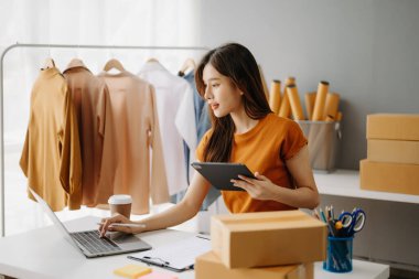 Moda blogcusu kavramı, genç Asyalı kadın video yayınında kıyafet satıyor. Tablet ve dizüstü bilgisayar kullanarak küçük işletme KOBİ 'si kurun.