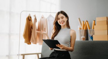 Genç işletme sahibi kadın paket kutusu hazırlıyor ve çevrimiçi siparişleri tablet, Alışveriş Online konsepti üzerinden müşteriye ulaştırmak için kontrol ediyor