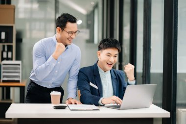 İki Asyalı işadamı modern ofiste birlikte otururken gülümsüyor. 