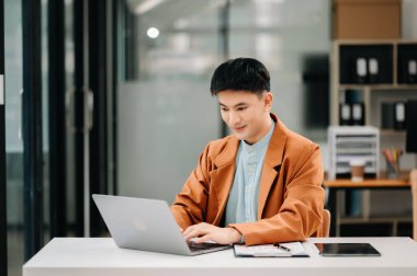 Modern ofiste dizüstü bilgisayarla çalışan çekici bir Asyalı.