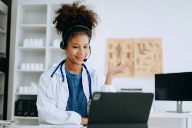 Çekici Afrikalı kadın doktor hastaya tıbbi tedaviyi ofisteki bir bilgisayarla açıklıyor.