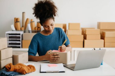 Başlangıçta küçük işletme KOBİ 'si, çevrimiçi siparişleri kontrol eden ve nakliye için paket hazırlayan Afrikalı kadın girişimci