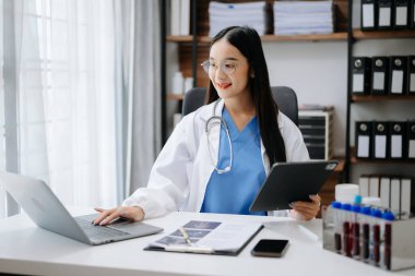 Hastanede çalışırken bilgisayarını kullanan Asyalı doktor ya da danışman.