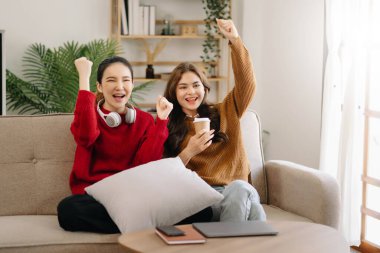 İki Asyalı güzel, gülümseyen genç kadın kanepede oturmuş, TV 'de komedi videosu izliyorlar. Oturma odasında etkinlik yaşam tarzı kavramı