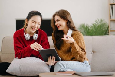 İki Asyalı öğrenci mutfaktaki dijital tablette ya da evdeki oturma odasında birlikte öğreniyor..