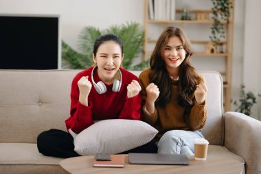 İki Asyalı güzel, gülümseyen genç kadın kanepede oturmuş, TV 'de komedi videosu izliyorlar. Oturma odasında etkinlik yaşam tarzı kavramı
