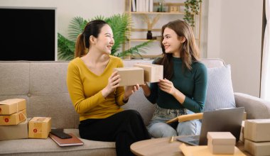 Küçük işletmeler kuran KOBİ sahipleri ürün satıyor, ev ofisinde kutularla çalışıyor, dizüstü bilgisayar kullanıyor