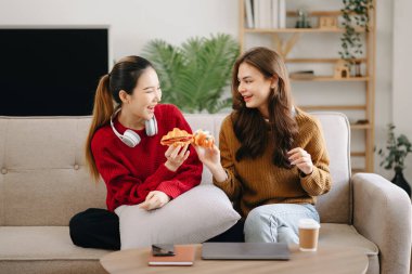 İki Asyalı güzel, gülümseyen genç kadın kanepede oturmuş, TV 'de komedi videosu izliyorlar. Oturma odasında etkinlik yaşam tarzı kavramı
