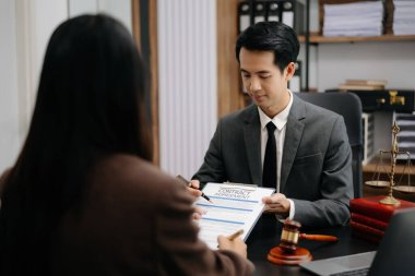 İş hukuku kavramı, Asyalı erkek avukat modern ofiste kadın girişimciye danışmanlık yapıyor.