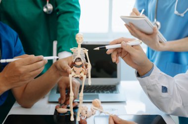 Tıbbi ekip bir masada oturup hastaları tartışıyor, internette çalışıyor ve hastane ya da tıp sektöründe bilgisayar kullanıyor.