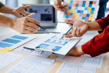 UX geliştiricisi ve ui tasarımcısı modern ofiste müşteri özeti ve renk kodu ile mobil uygulama arayüzü kablo tasarımı hakkında beyin fırtınası yapıyorlar