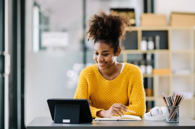 Modern üniversite kütüphanesinde online okuyan mutlu genç Afrikalı kız öğrenci