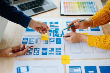 UX geliştiricisi ve ui tasarımcısı modern ofiste müşteri özeti ve renk kodu ile mobil uygulama arayüzü kablo tasarımı hakkında beyin fırtınası yapıyorlar