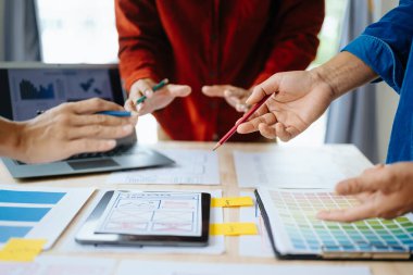 UX geliştiricisi ve ui tasarımcısı modern ofiste müşteri özeti ve renk kodu ile mobil uygulama arayüzü kablo tasarımı hakkında beyin fırtınası yapıyorlar