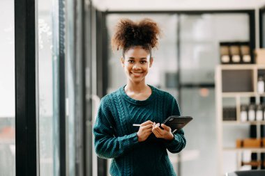 Modern üniversite kütüphanesinde online okuyan mutlu genç Afrikalı kız öğrenci