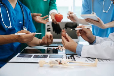 Tıbbi ekip bir masada oturup hastaları tartışıyor, internette çalışıyor ve hastane ya da tıp sektöründe bilgisayar kullanıyor.