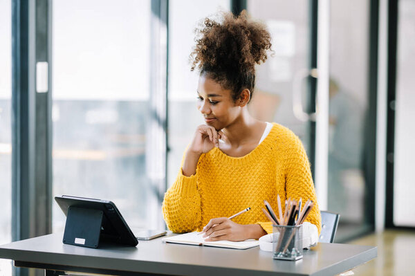 happy young African female student studying online in modern college library