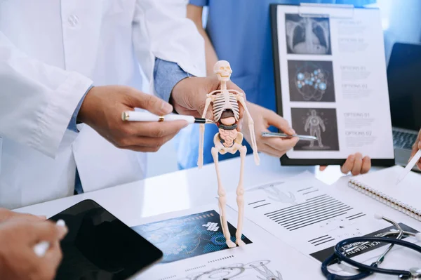 Tıbbi ekip, beyaz laboratuvar önlüklü ve ameliyat önlüklü doktorlarla toplantı yapıyor. Masada oturmuş, internette çalışan hastaları tartışıyorlar. Tıp endüstrisinde bilgisayar kullanıyorlar.