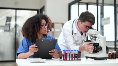 Modern Tıbbi Araştırma Laboratuvarı: Mikroskop kullanarak çalışan iki bilim adamının portresi, Örnekler analiz ediliyor. Tıp, Biyoteknoloji Geliştirme