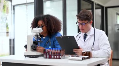 Modern Tıbbi Araştırma Laboratuvarı: Mikroskop kullanarak çalışan iki bilim adamının portresi, Örnekler analiz ediliyor. Tıp, Biyoteknoloji Geliştirme