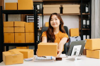 Başlangıçta küçük işletme KOBİ 'si, Asyalı kadın girişimci çevrimiçi siparişleri kontrol ediyor ve nakliye için paketler hazırlıyor