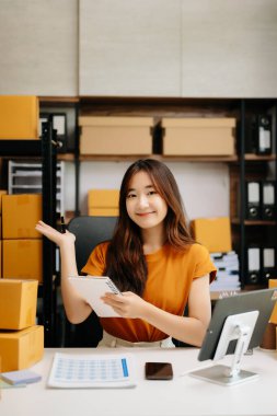 Başlangıçta küçük işletme KOBİ 'si, Asyalı kadın girişimci çevrimiçi siparişleri kontrol ediyor ve nakliye için paketler hazırlıyor