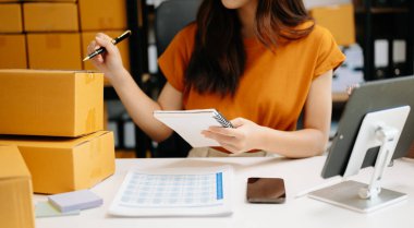 Genç Asyalı iş kadını, paket kutusu hazırla ve çevrimiçi alışveriş konseptine çevrimiçi teslimat için online siparişleri kontrol et.