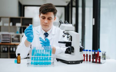 Modern tıbbi araştırma laboratuvarı. Erkek bilim adamı mikro pipetlerle çalışıyor ve biyokimyasal örnekleri analiz ediyor.