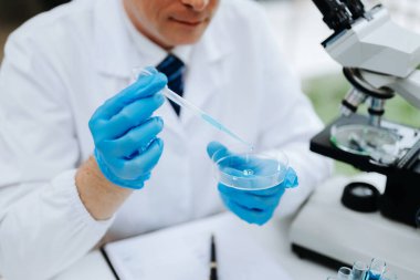Kimya laboratuvarında sıvı karıştıran bir bilim adamı. Test tüpleriyle çalışan bir araştırmacı. 