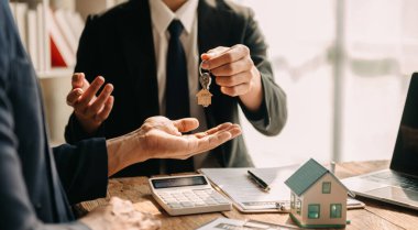 Satıcı, modern ofis, iş ve sözleşme imzalama konseptinde alıcıya anahtar veriyor.