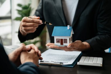 Emlakçı yeni evi müşteriye sunuyor. İpotek kredisine danışmanlık yapan komisyoncu