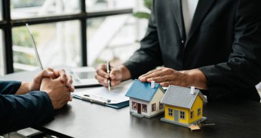 Emlakçı yeni evi müşteriye sunuyor. İpotek kredisine danışmanlık yapan komisyoncu