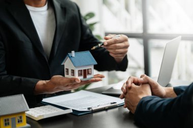 Emlakçı yeni evi müşteriye sunuyor. İpotek kredisine danışmanlık yapan komisyoncu
