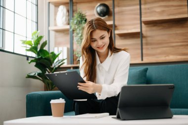 Oturma odasında çalışma odasında, merkez ofisteki kanepede otururken tablet kullanan güzel bir kadın.