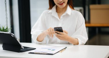 Akıllı telefon ve dijital tablet kullanan bir iş kadını. Bulanık arkaplanda yakın plan