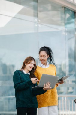 Asyalı öğrenciler kampüs parkını inceliyor. Gençler birlikte vakit geçiriyorlar.