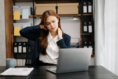 Ofisinde uzun bir gün geçirdikten sonra boynu ağrıyan Asyalı genç iş kadını ofis çalışanı. 