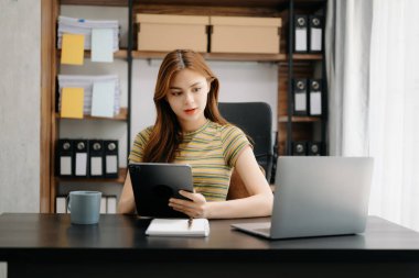 Yaratıcı ofiste dijital tablet tutan kendinden emin genç Asyalı kadın..