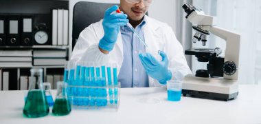 Kimya laboratuvarında sıvı karıştıran bir bilim adamı. Test tüpleriyle çalışan bir araştırmacı. 