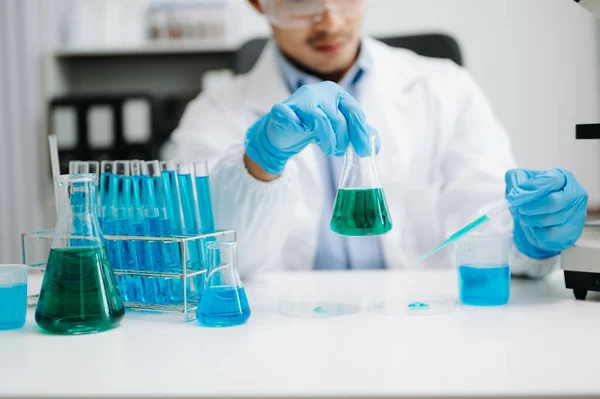 Male biotechnologist testing new chemical substances in a laboratory. with micro pipettes analyzing biochemical samples, advanced science chemical laboratory for medicine.